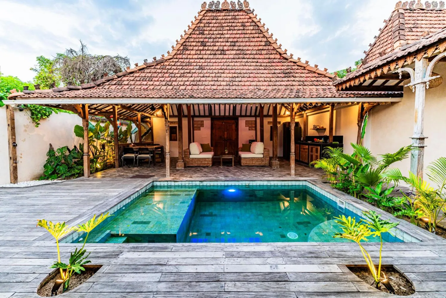 The grand tiled joglo roof of a Sundara villa above its private turquoise pool